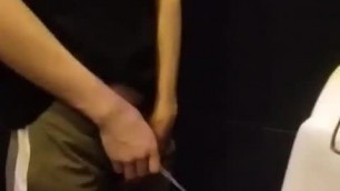 A male is pissing in the toilet.
